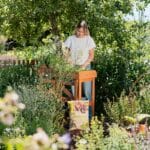 Frau gärtnert an Pflanztisch im grünen Garten