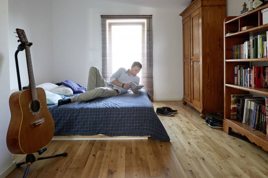 Mann liest Buch auf Bett im Schlafzimmer