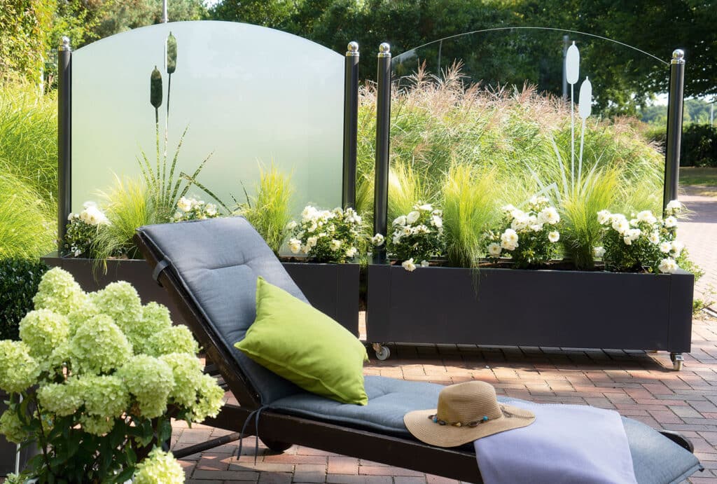 Moderne Gartenlounge mit Sichtschutz und Pflanzenkübeln