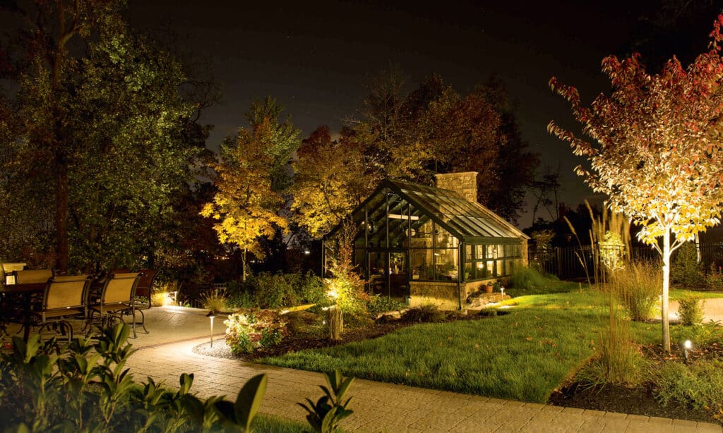 Beleuchteter Garten mit Gewächshaus bei Nacht
