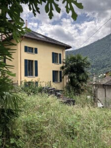 Gelbes Haus mit grünen Fensterläden und Bergkulisse