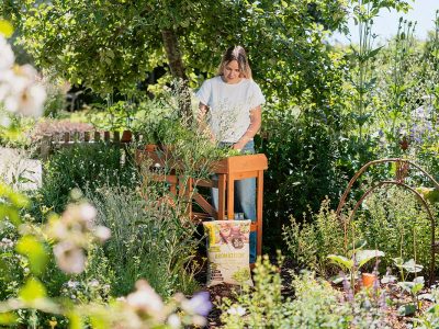Frau gärtnert an Pflanztisch im grünen Garten