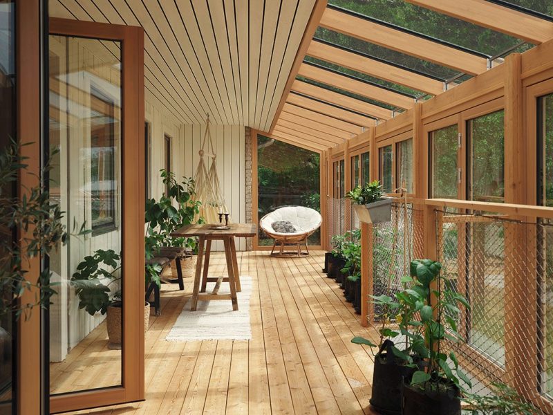 Holzveranda mit Glasdach, Pflanzen und Sitzbereich